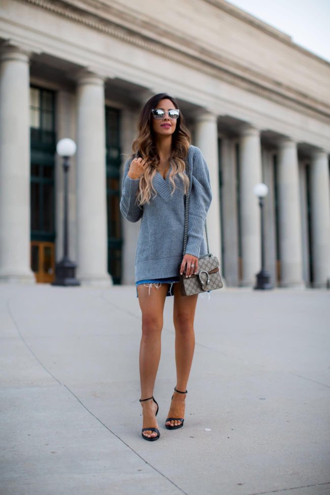 fashion blogger mia mia mine wearing an oversized gray sweater and denim mini skirt