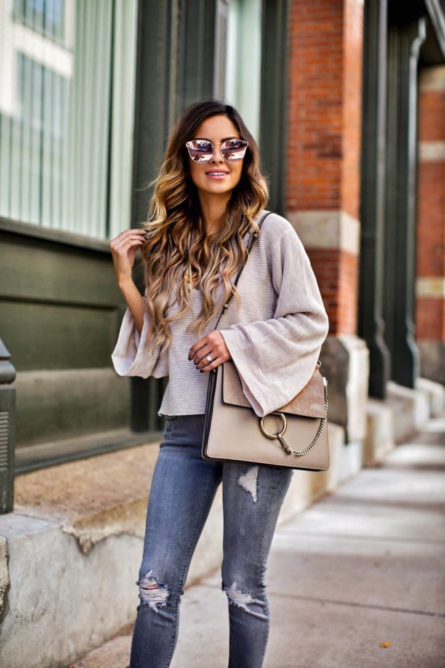 fashion blogger mia mia mine wearing a v-neck sweater by free people and grey jeans from express