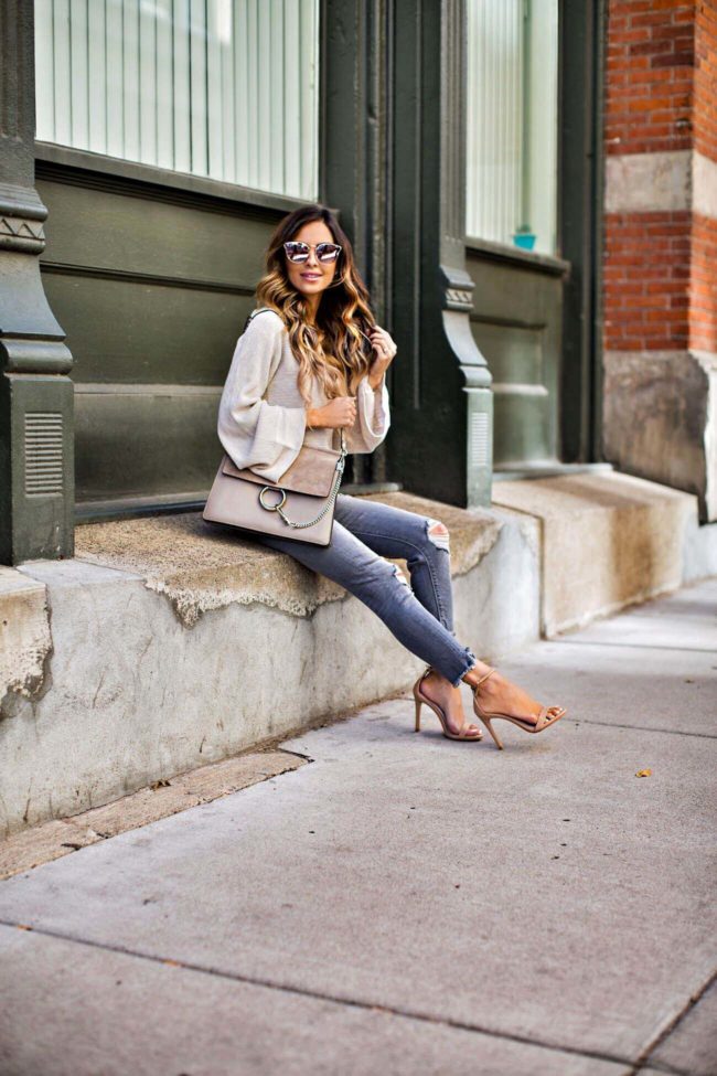 mia mia mine wearing a fall sweater by free people and grey ripped jeans