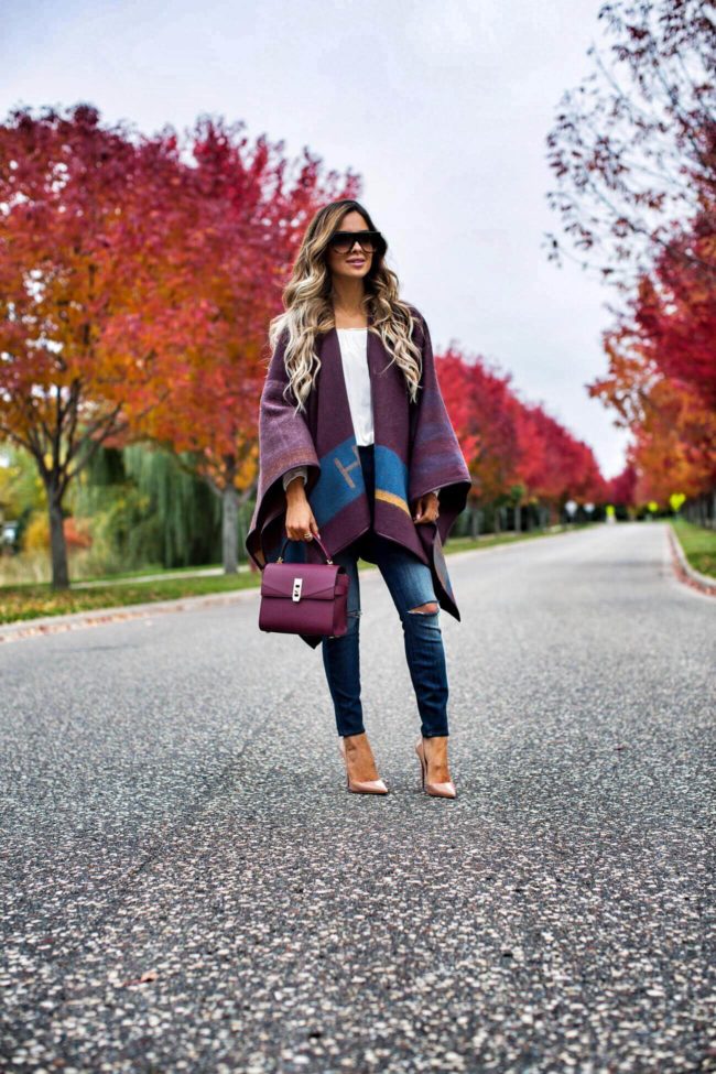 fashion blogger mia mia mine wearing skinny jeans and a fall cape from henri bendel