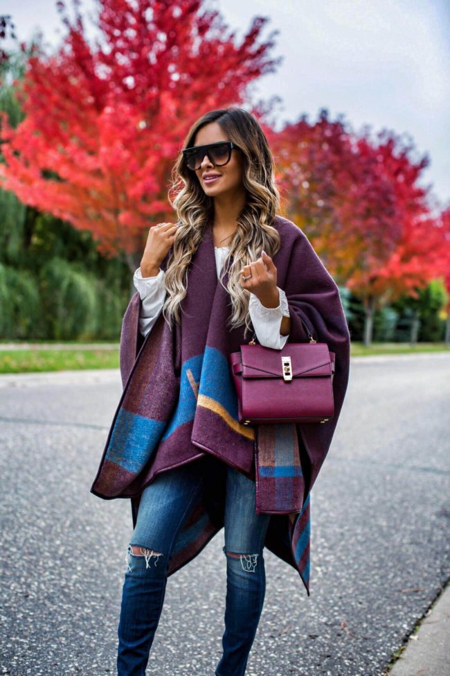 fashion blogger mia mia mine wearing a burgundy cape from henri bendel