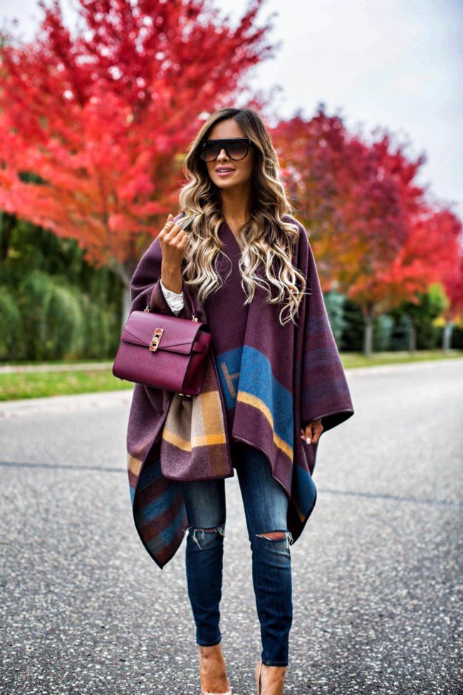 fashion blogger mia mia mine wearing a burgundy fall cape from henri bendel