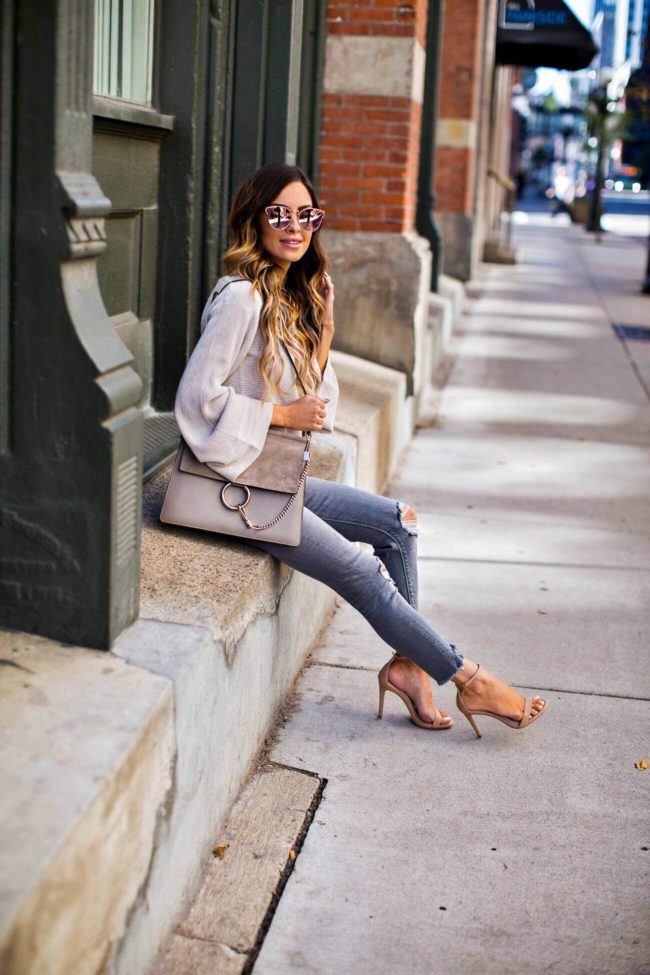 fashion blogger mia mia mine wearing grey ripped jeans and a free people sweater