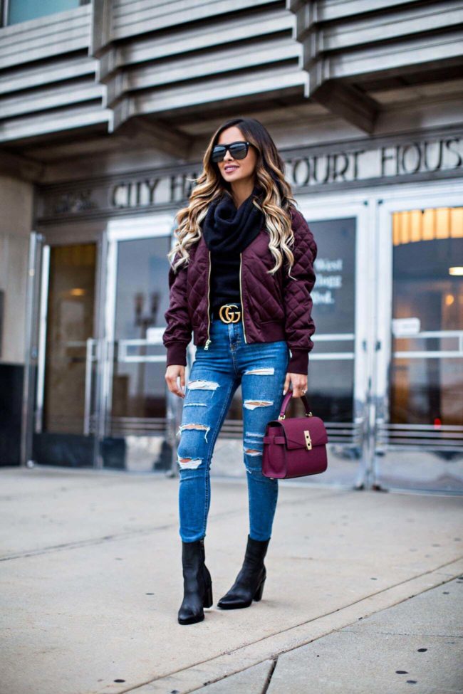 fashion blogger mia mia mine wearing a burgundy bomber jacket from express and ripped jeans