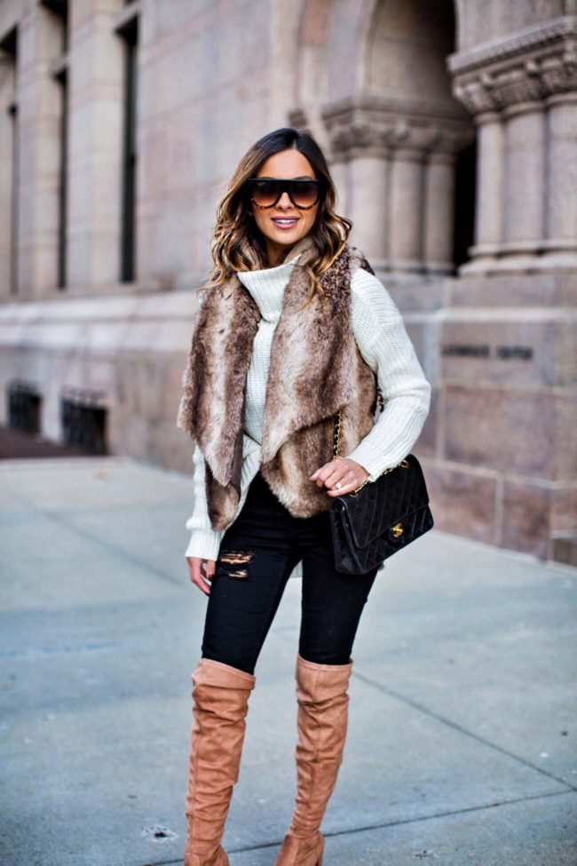 fashion blogger mia mia mine wearing a faux fur vest from bloomingdale's and steve madden over-the-knee boots