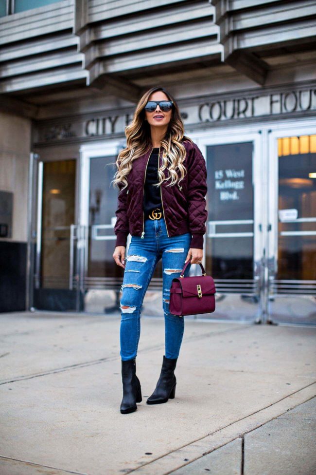 fashion blogger mia mia mine wearing a burgundy bomber jacket from express and ripped jeans from topshop
