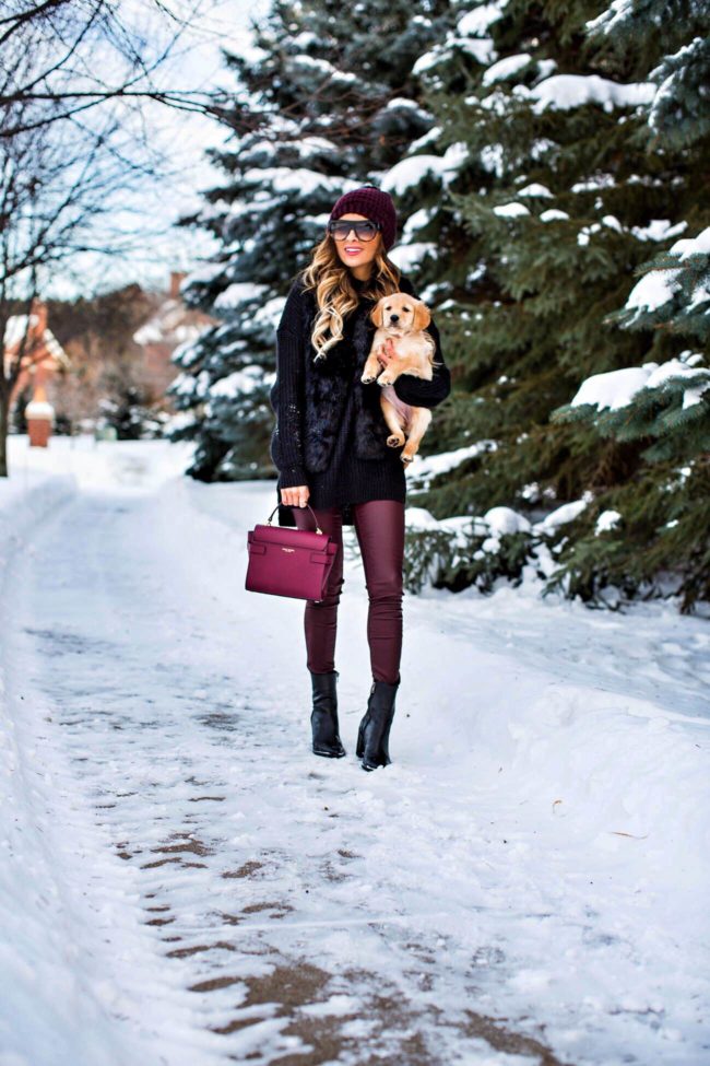 fashion blogger mia mia mine holding her golden retriever puppy in the snow