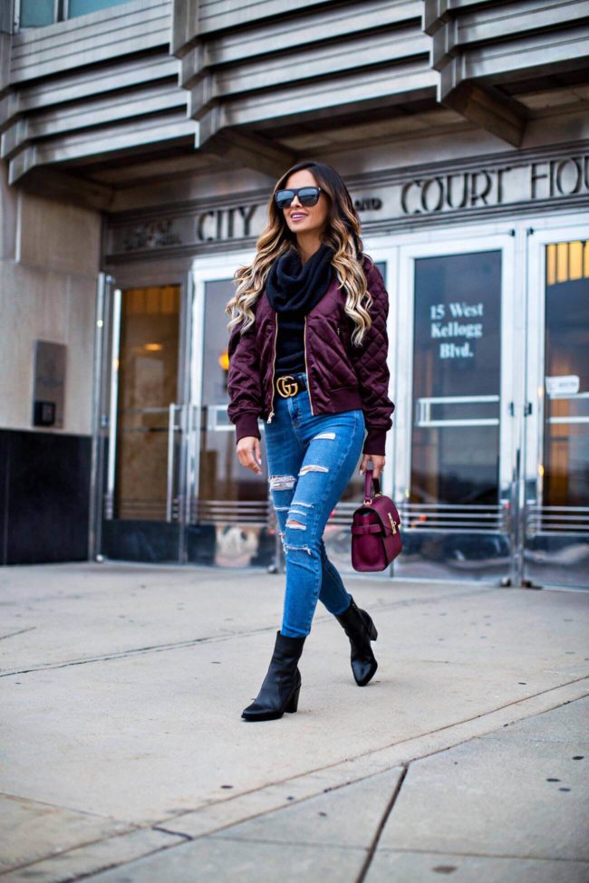 fashion blogger mia mia mine wearing a burgundy bomber jacket from express and ripped jeans