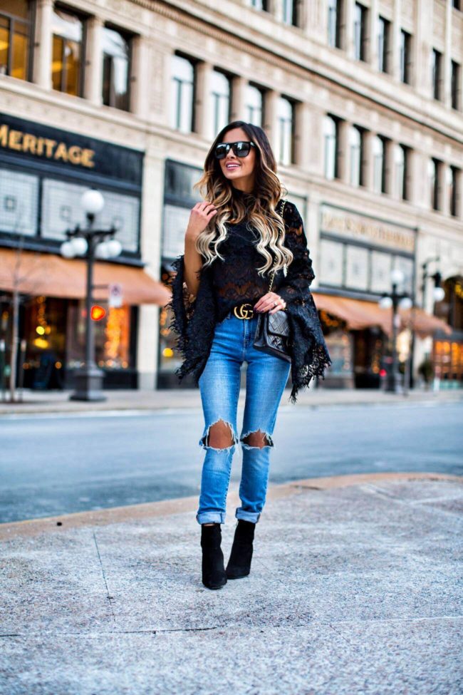 fashion blogger mia mia mine wearing a black lace bell sleeve top revolve and a gucci double g buckle belt