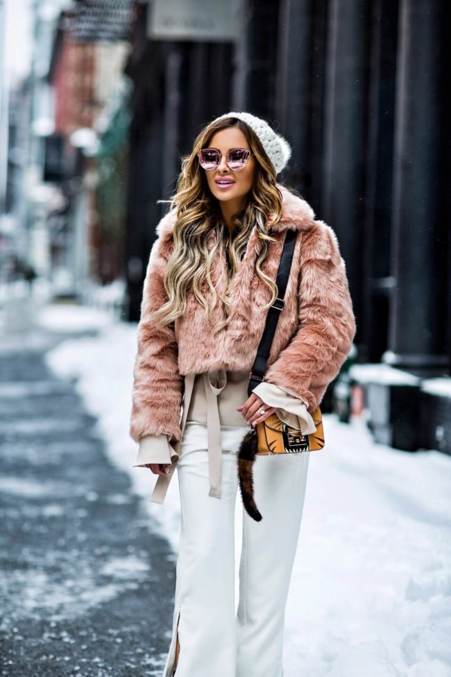 fashion blogger mia mia mine wearing a faux fur pink coat and white pants at NYFW
