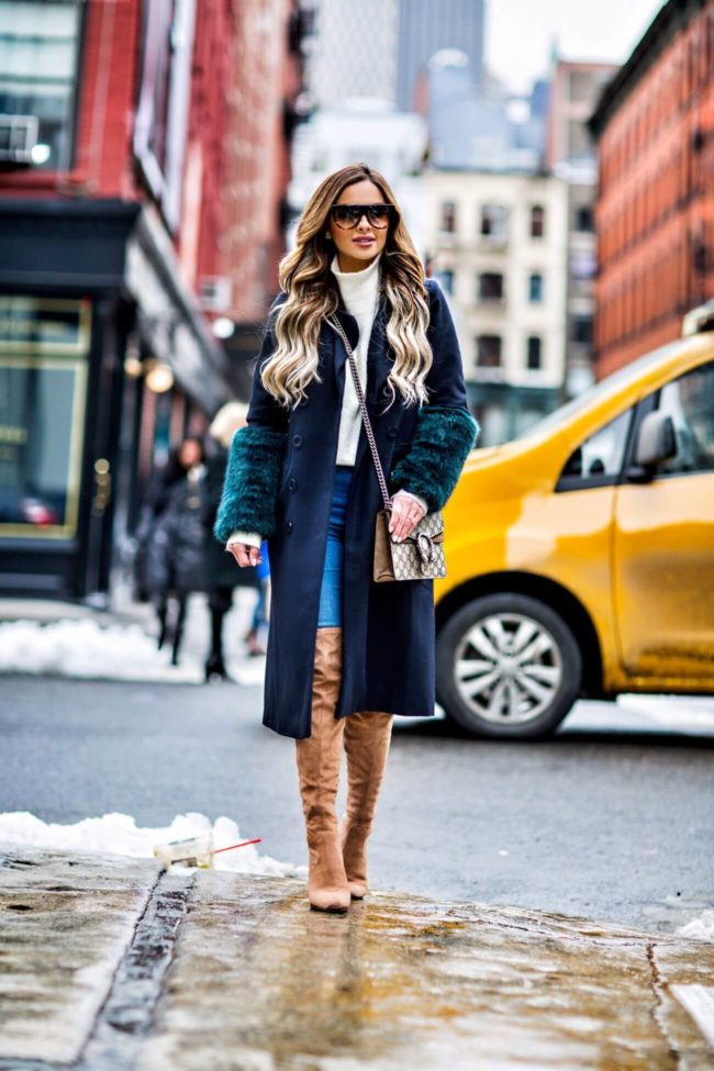 fashion blogger mia mia mine wearing a faux fur coat and over-the-knee boots at new york fashion week 2017