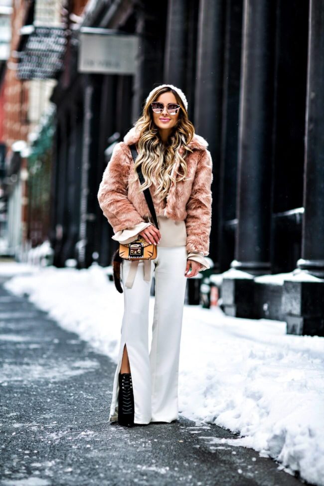 fashion blogger mia mia mine wearing a blush faux fur jacket and white pants at NYFW 2017
