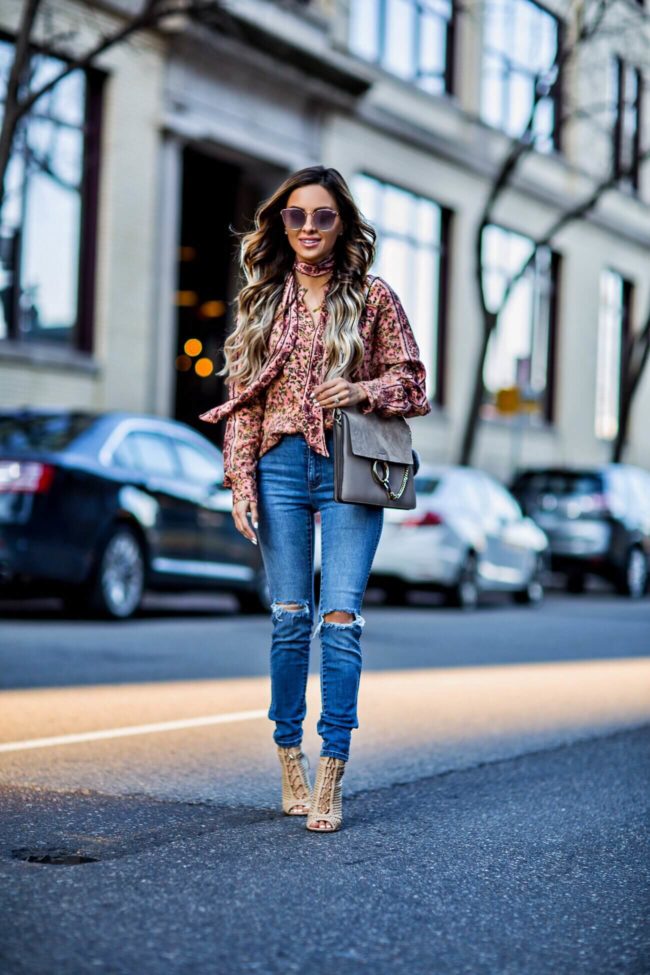 fashion blogger mia mia mine wearing a free people floral print top and skinny jeans from revolve