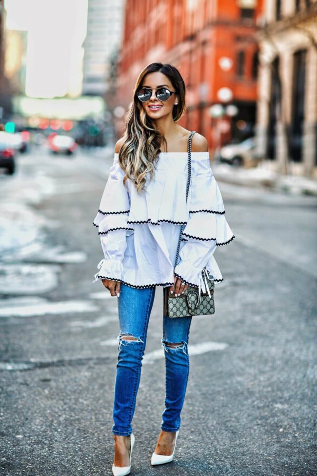 fashion blogger mia mia mine wearing a ruffle white top by few moda and skinny jeans from revolve