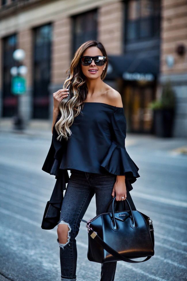 fashion blogger mia mia mine wearing an off-the-shoulder statement sleeve black top by few moda and levi's jeans