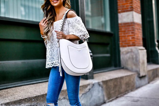 mn fashion blogger mia mia mine wearing a white lace off-the-shoulder top and carrying a white henri bendel hobo bag