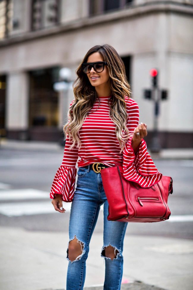 fashion blogger mia mia mine wearing a red striped bell sleeve top and a gucci double g buckle belt