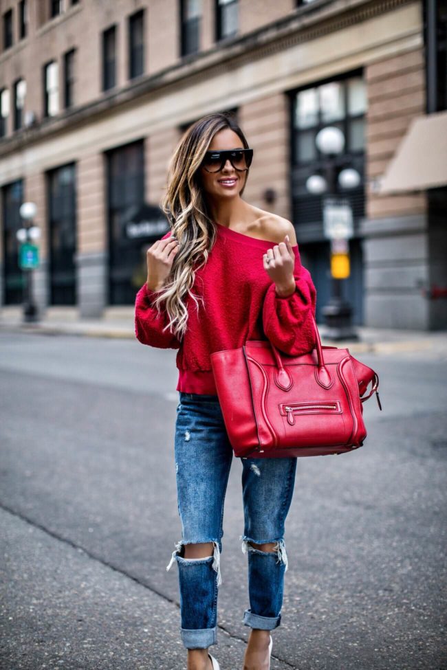 mn fashion blogger mia mia mine wearing a red off-the-shoulder sweatshirt and grlfrnd jeans from revolve