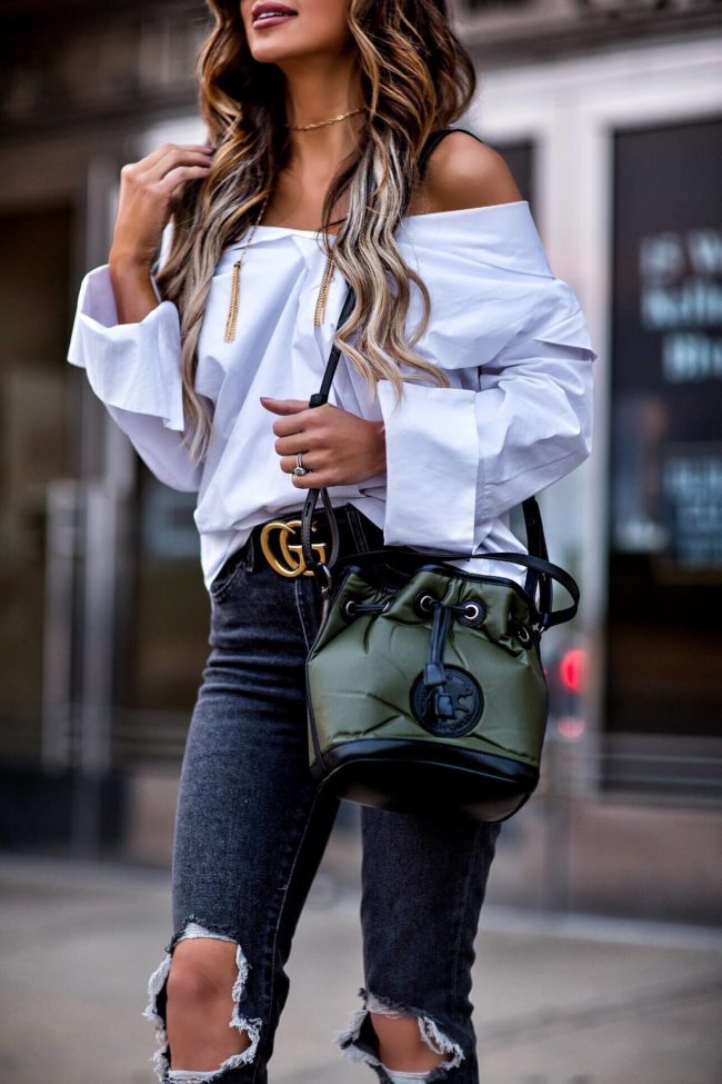 fashion blogger mia mia mine wearing an off-the-shoulder white button down and a drawstring bag by hunting world nyc