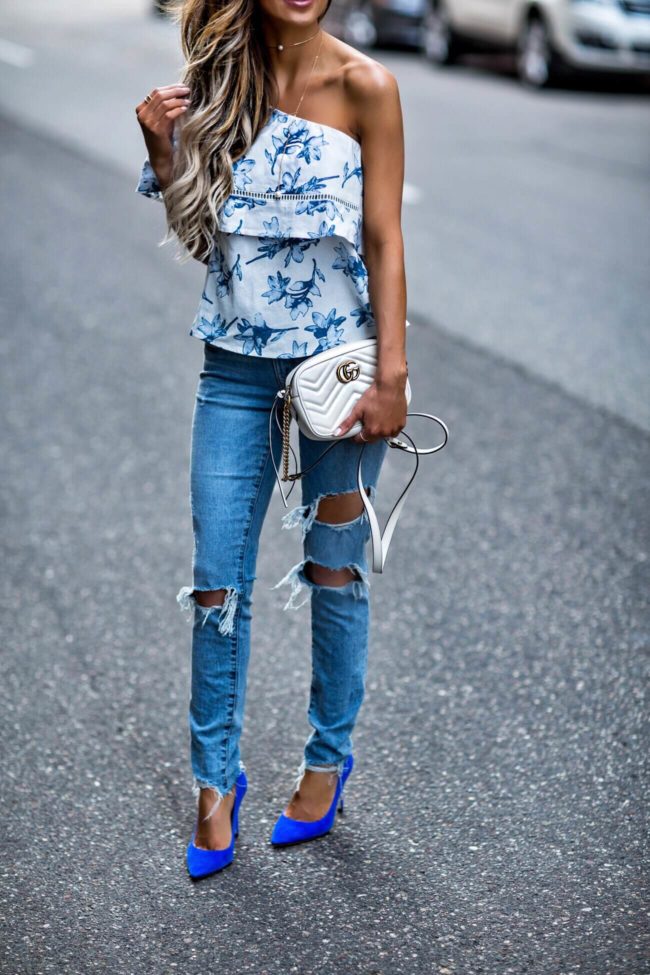 fashion blogger mia mia mine wearing a floral one-shoulder top and grlfrnd jeans from revolve