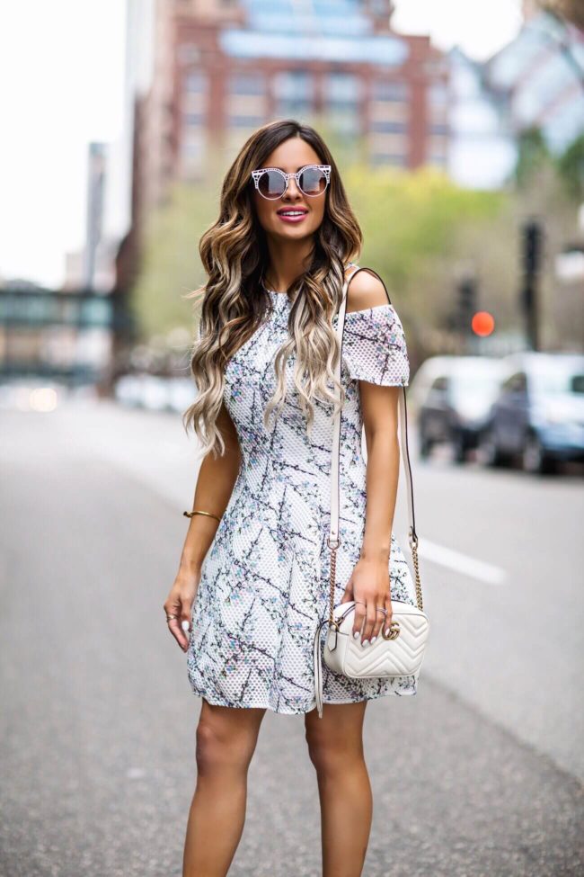 fashion blogger mia mia mine wearing a floral mini dress from revolve and a gucci marmont white bag and white quay sunglasses