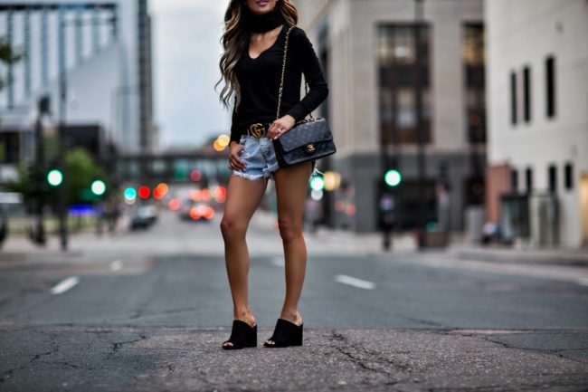 fashion blogger mia mia mine wearing a black cutout sweater and a gucci double g buckle belt