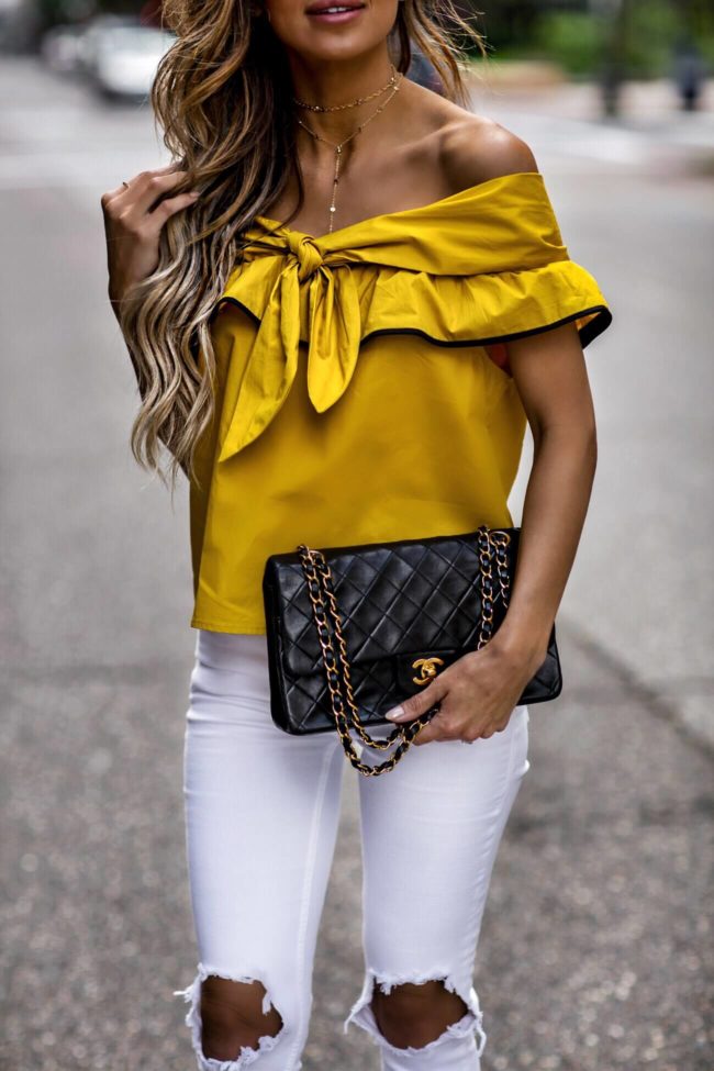 fashion blogger mia mia mine wearing a mustard yellow top from revolve and a gold choker