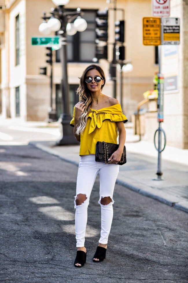fashion blogger mia mia mine wearing a mustard top from revolve and free people white jeans