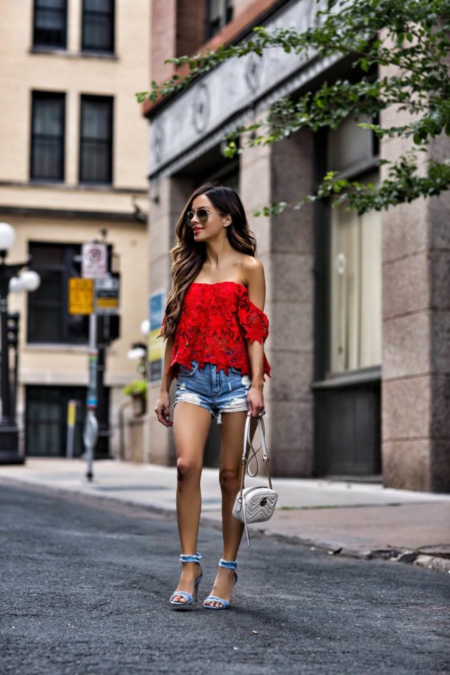 fashion blogger mia mia mine wearing a red lace off-the-shoulder top from nordstrom and ripped denim shorts from revolve with a gucci marmont bag