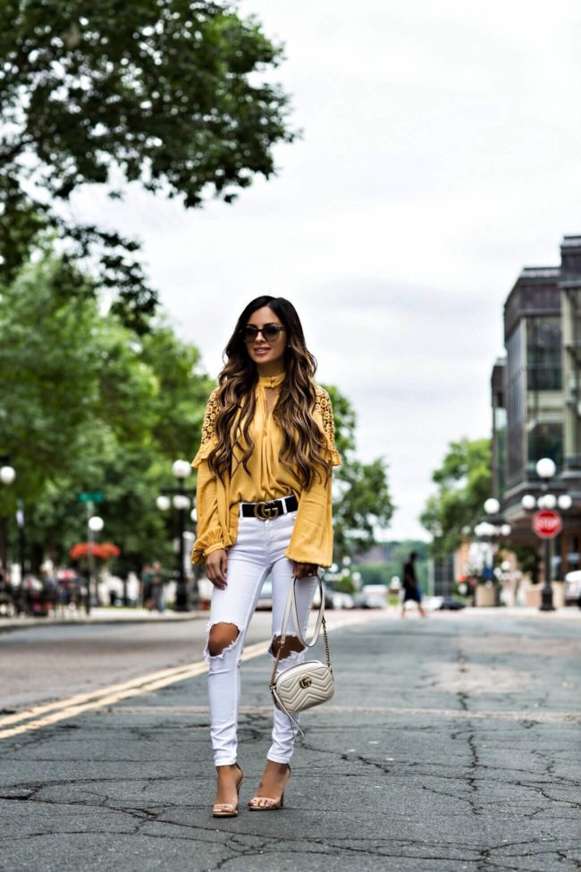 fashion blogger mia mia mine wearing a yellow free people top from macy's and free people white ripped skinny jeans