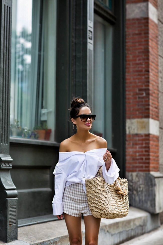 fashion blogger mia mia mine wearing a white button down white off-the-shoulder top and gingham shorts from revolve