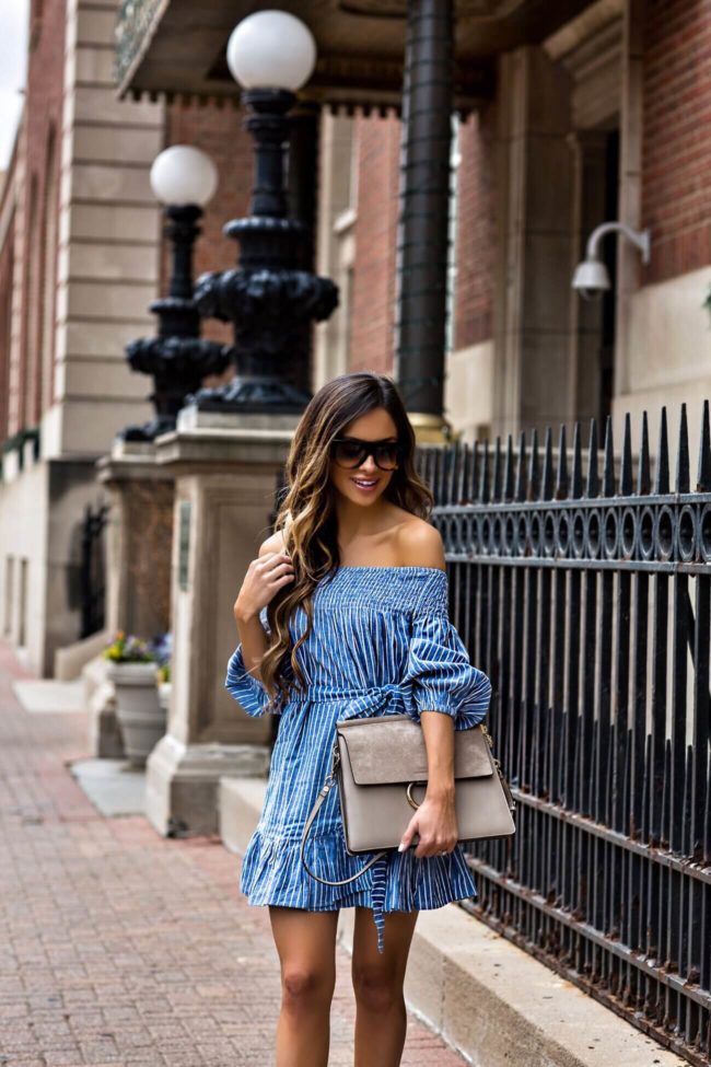 fashion blogger mia mia mine wearing a striped off shoulder blue dress from revolve