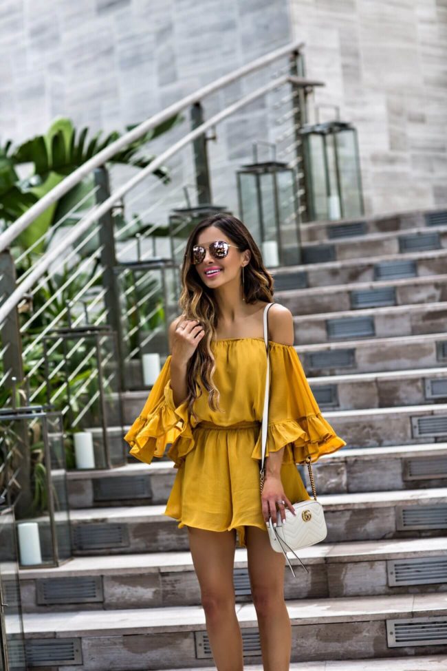 fashion blogger mia mia mine wearing a mustard romper from revolve and a gucci marmont mini bag