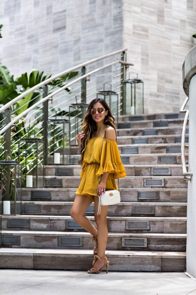 fashion blogger mia mia mine wearing a yellow off-the-shoulder romper from revolve