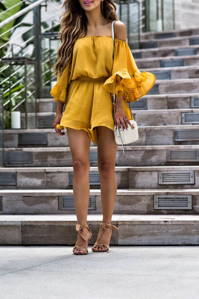 fashion blogger mia mia mine wearing a yellow off-the-shoulder romper and schutz nude heels from amazon