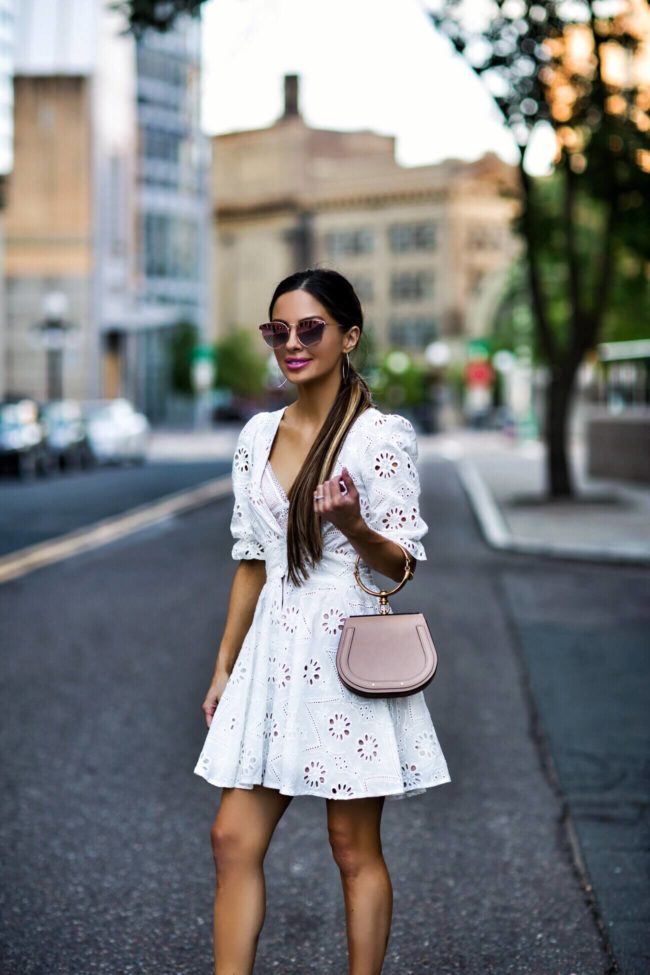 fashion blogger mia mia mine wearing a white eyelet dress from revolve and a chloe nile pink bag and quay pink sunglasses