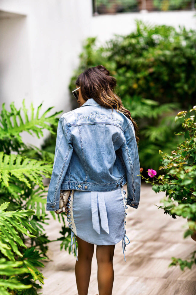 fashion blogger mia mia mine wearing a heartbreaker denim jacket and a blue side lace-up dress from revolve