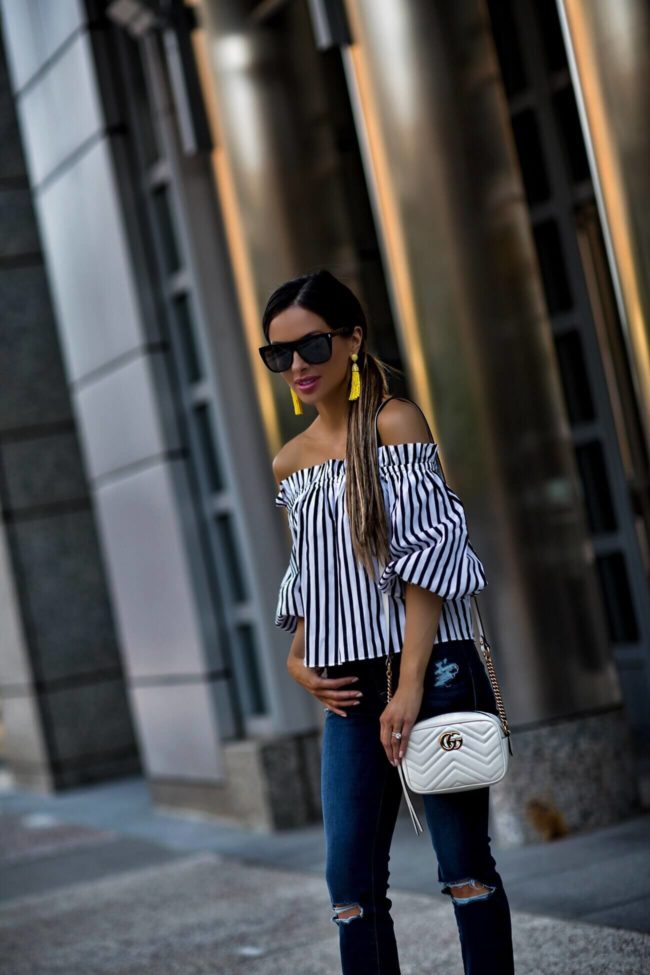 fashion blogger mia mia mine wearing an off-the-shoulder striped top and yellow baublebar earrings