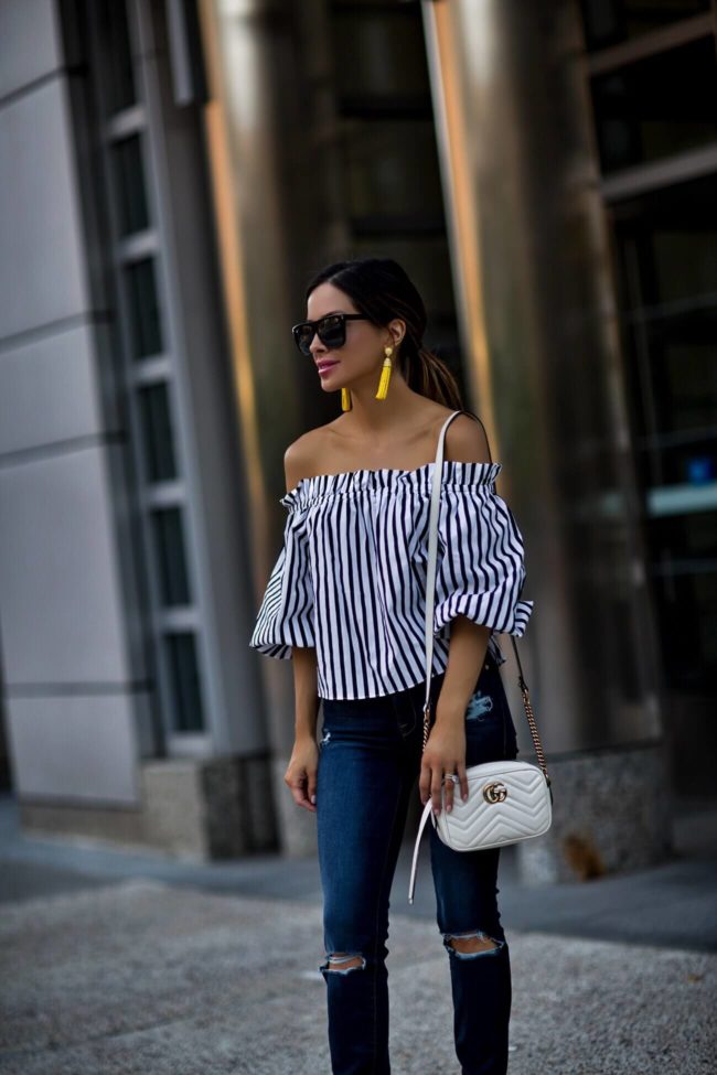 fashion blogger mia mia mine wearing an off-the-shoulder striped top from revolve and a gucci marmont white bag