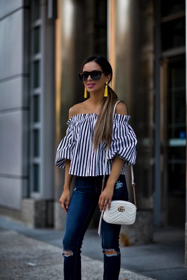 fashion blogger mia mia mine wearing a striped off-the-shoulder top from revolve and yellow earrings 