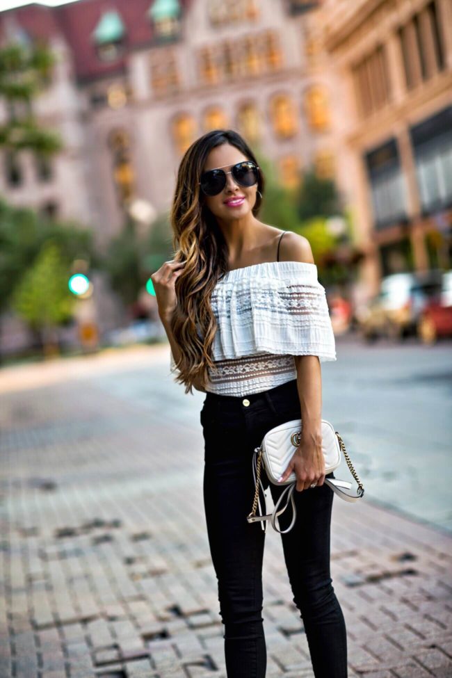 fashion blogger Maria Vizuete from the blog Mia Mia Mine wearing an off-the-shoulder white shirt and black skinny jeans