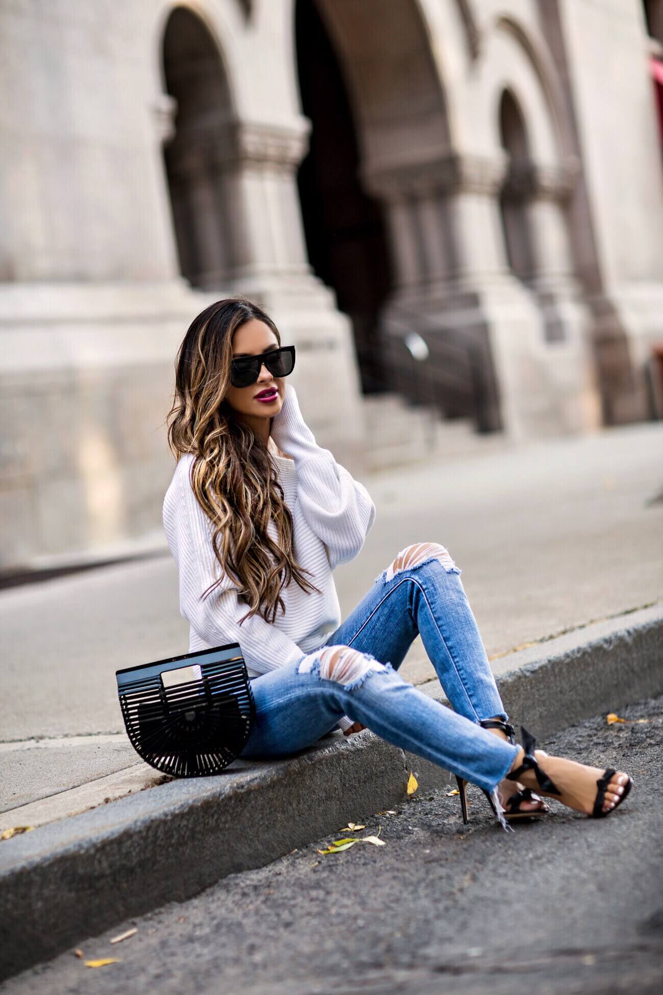 fashion blogger mia mia mine wearing saint laurent sunglasses and a white oversized sweater from intermix