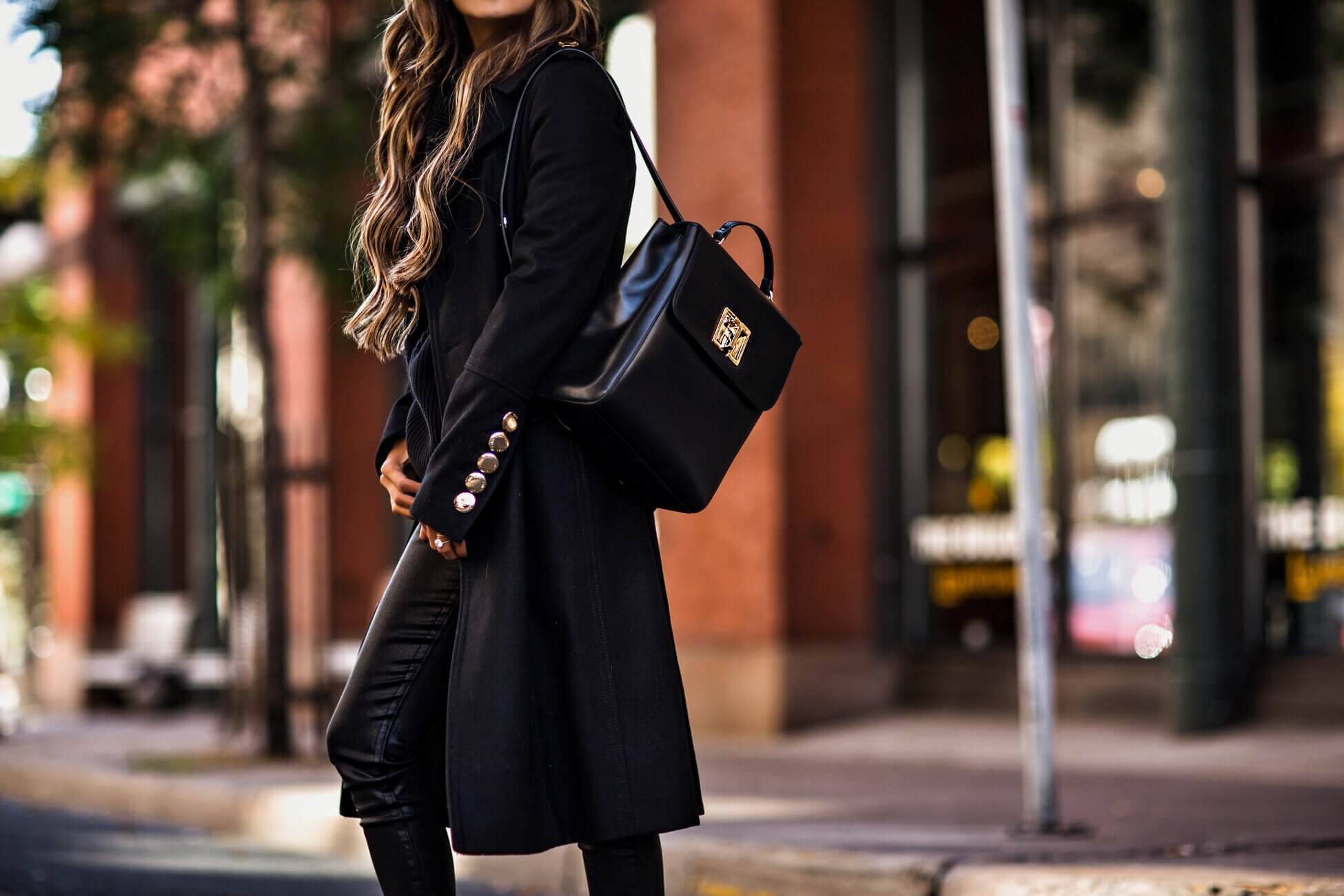 fashion blogger mia mia mine wearing a tommy hilfiger black backpack and a black coat from macy's