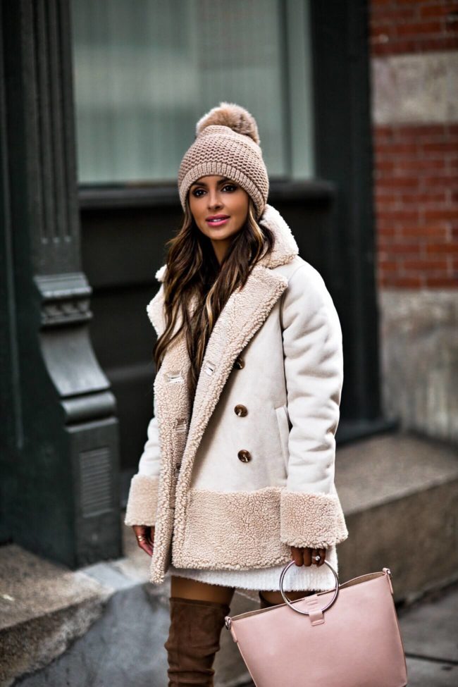 Mia Mia Mine wearing a white winter jacket and pom beanie from Bloomingdales