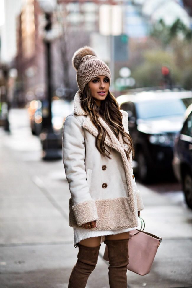 Fashion blogger Mia Mia Mine wearing a pom beanie and a faux shearling jacket from Bloomingdales