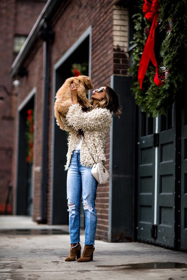 fashion blogger mia mia mine wearing a shag jacket and holding a golden retriever puppy