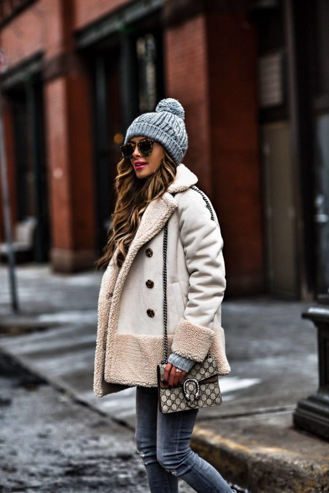 fashion blogger mia mia mine wearing a shearling jacket and gray beanie hat