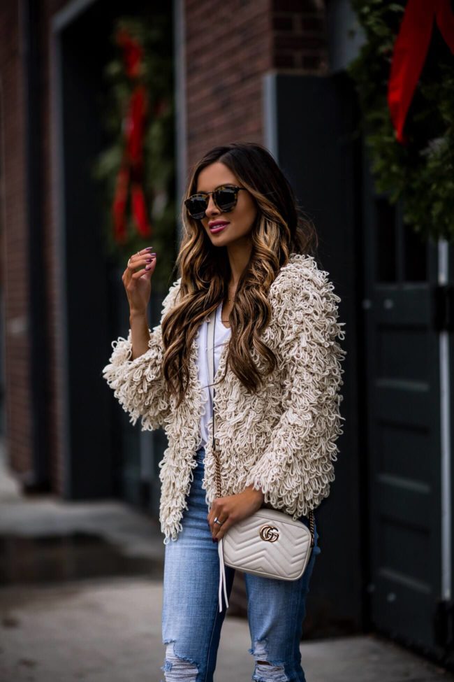 fashion blogger mia mia mine wearing a white shag cardigan and karen walker sunglasses