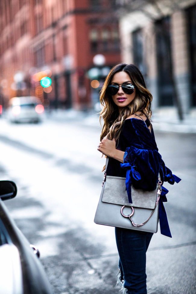 fashion blogger mia mia mine wearing a blue velvet top with ribbons and a chloe faye bag