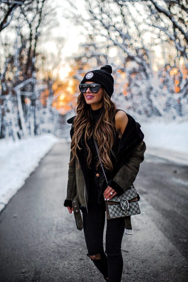 fashion blogger mia mia mine wearing a herschel beanie and a black bodysuit in the snow